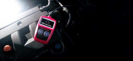 OBD2 or OBD scanner tool on car engine compartment for engine system analysis to fixing car engine system , Car maintenance service concept photo