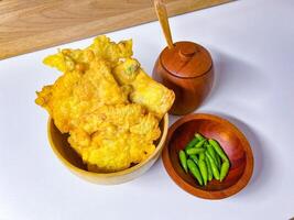 Traditional Indonesian Food Called Tempe Goreng or Mendoan or Fried Tempeh with Flour Batter served with Green Cayenne Pepper or Green Colored Chilli on Isolated White Background. High quality photo