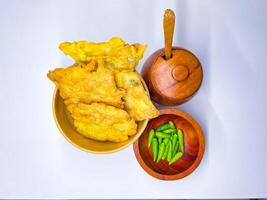 Traditional Indonesian Food Called Tempe Goreng or Mendoan or Fried Tempeh with Flour Batter served with Green Cayenne Pepper or Green Colored Chilli on Isolated White Background. High quality photo