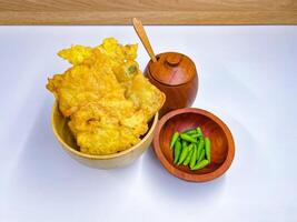 Traditional Indonesian Food Called Tempe Goreng or Mendoan or Fried Tempeh with Flour Batter served with Green Cayenne Pepper or Green Colored Chilli on Isolated White Background. High quality photo
