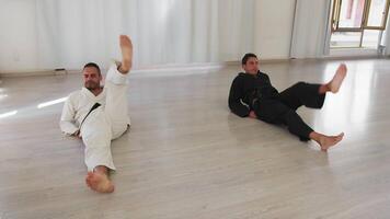 Hommes mensonge sur le sol faire chaud en haut jambe des exercices pour karaté session video