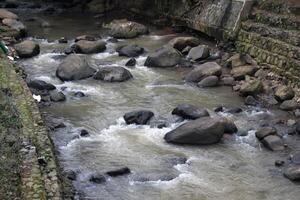 Close up view of water flowing between large rocks at the bottom of the Ciliwung River photo