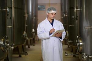 Professional winemaker controlling wine making process and quality at winery factory photo