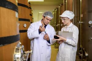 Professional winemaker controlling wine making process and quality at winery factory photo