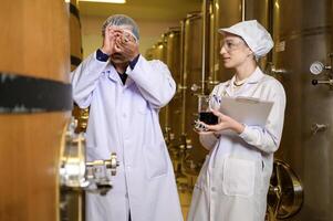 Professional winemaker controlling wine making process and quality at winery factory photo