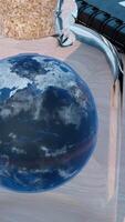 Rotating Earth globe inside glass bottle. Design. Surreal illustration of the planet on the table, notebook and a pen. video