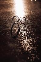 Two wedding rings are on a table with a dark background photo