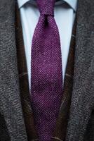 A Close-Up of a Purple Herringbone Necktie Worn With a Brown and Grey Suit photo