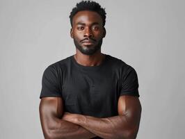 Man Wearing Black T-Shirt With Arms Crossed, Standing Against Gray Background photo