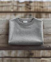 Folded Gray Crew Neck Sweater on Rustic Wooden Surface photo