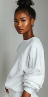 Stylish Black Woman in White Sweatshirt Posing Against a Grey Background photo