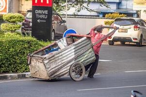 A scavenger pulls his cart along a street. the concept of poverty and environmental cleanliness, Indonesia, 6 June 2024. photo