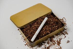 tobacco and some cigarettes around it with a white background photo