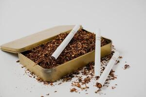 tobacco and some cigarettes around it with a white background photo