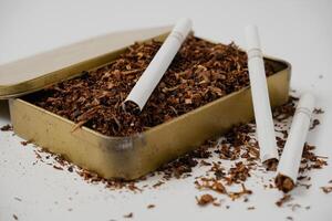 tobacco and some cigarettes around it with a white background photo