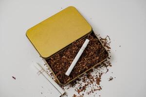 tobacco and some cigarettes around it with a white background photo