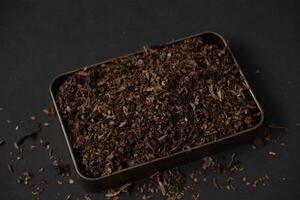 fine tobacco in a gold iron box on a black table photo