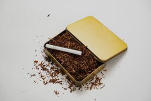 tobacco and some cigarettes around it with a white background photo