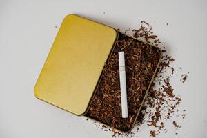 tobacco and some cigarettes around it with a white background photo