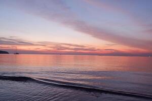 a sunset over the ocean with a boat in the water photo