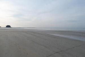 a beach with a lone person walking on it photo