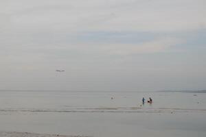a person standing on a beach with a kite flying in the sky photo