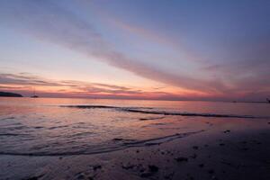 a sunset on a beach with waves and a sky photo