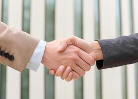 Close up of hand of Two business people shaking hands,blurred building background photo