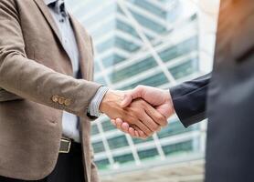 Close up of hand of Two business people shaking hands,blurred building background photo