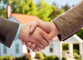Close up of handshake with house for sale in background photo