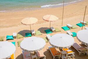 Ariel top view of relaxing place on the beach with chairs and sun loungers with umbrellas at the white sand beach and beautiful blue waters on the island of Koh Larn. Sunbathing place and relax. photo