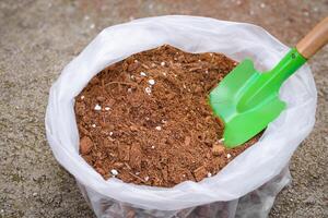 Soil fertilizer peat moss or cocopeat in bags and soil shovels are used for planting crops or preparing or mixing fertilizer. Top view of peat moss fertilizer bag selective focus on blurred background photo