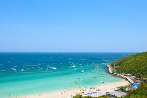 Beautiful tropical beach on Koh Larn is a beach with white sand and crystal clear water and groups of tourists on the beach and boats in the sea. Ariel top view of beautiful beaches and islands. photo