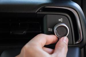 Hand turning the air conditioning control button inside the car for changing the air conditioning mode in a luxury and modern car, year 2024. photo