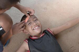 Boy doing wound dressing care and bandaging patient head on road surface background,Asian young boy lying smiling on floor,children accident,Wound dressing on kid,Happy accident,childhood accidents. photo