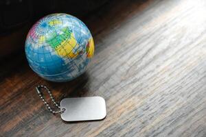 Earth Globe and Dog Tag on wood pattern work desk and soft sunlight background,Desktopequipment,Dog Tag empty,World and map of Americas,Top view with copy space,Concept of Travel and Work. photo