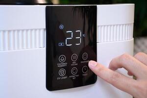 Close up of hand pressing button on thermostat or air conditioner in smart farm or modern home. Temperature regulator or air conditioner cooling and fingers pressing buttons in a hydroponic farm. photo
