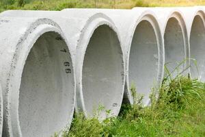 Concrete pipe circle shape for concept of construction work and drainage systems were arranged in an orderly manner on grass and soft sunlight background. photo