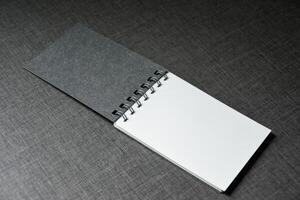 Blank white and black notebook on dark table wooden pattern background,Blank black cover template with copy space for design,notebook isolated on dark background, concept of design and business. photo
