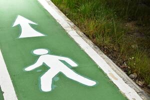 White line walking lane on green road surfaces exercise for towards the light at outdoor park in grass and soft sunlight background concept of exercise and health. photo