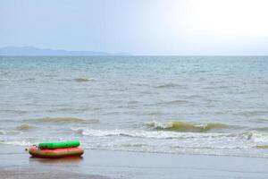 Banana boats or inflatable rubber boat on a deserted beach and dirty sea water conveys problems environmental pollution and water pollution in sea wave and mountain with fog background. photo