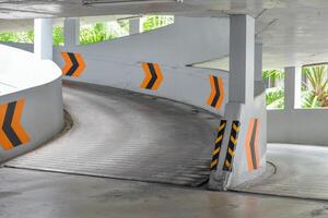 Entrance to the circular parking building go down and yellow warning symbol in natural and sunlight background at public parking. photo