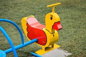 Yellow duck-shaped carousel or children's merry-go-round in the playground on green grass background. photo