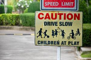 Sign caution speed limit drive slow children at play on yellow background at park in evening sunset, playground sign,landscape garden background. photo
