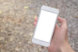 Close up of man hand holding modern smartphone mockup with blank white screen. Hand showing white screen of smartphone in ground blurred background. photo
