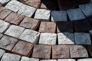 Texture abstract granite cobblestone pavement background is gray and brown stone wall close-up with shadow and soft sunlight. photo