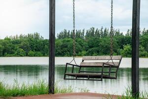 Beautiful landscapes of lake and forest there is a lonely swing by the lake and light hitting the water surface on sky cloudy with soft sunlight background. photo