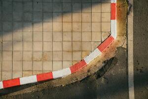 Top-view of red and white grid patterned sidewalk or footpath and road with traffic lines show the texture of concrete in vintage tones. photo