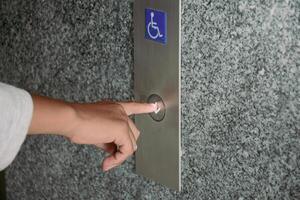 Close-up hand pressing the button for the disabled elevator to go down the building. photo