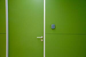 Green door with coded door lock or code keypad on a green wall background and soft light for concept of Interior design and home safety. photo